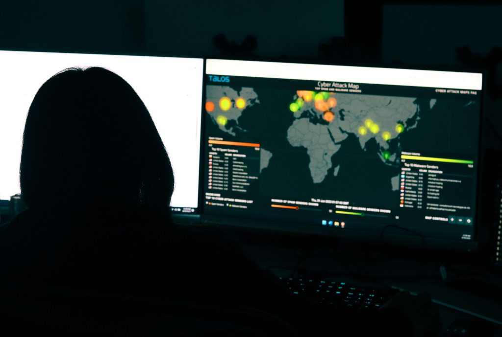 Gridware employee sitting at computer screen looking at world wide cyber threats pointed on a map